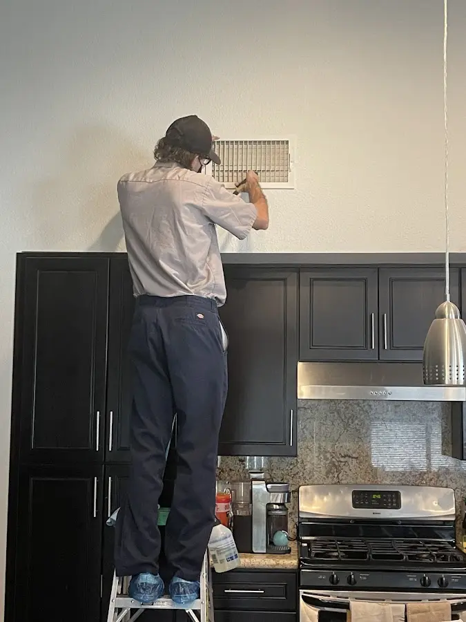 Technician inspecting an air vent during HVAC service in Seaside